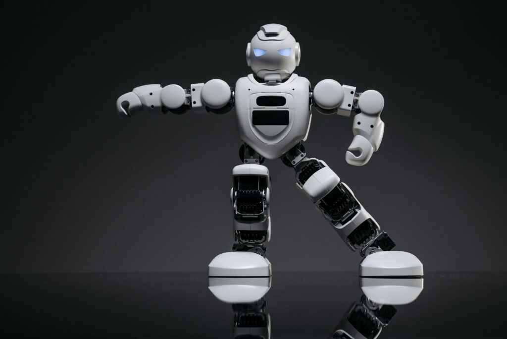 Close-up of a white toy robot with glowing eyes on a reflective black surface.